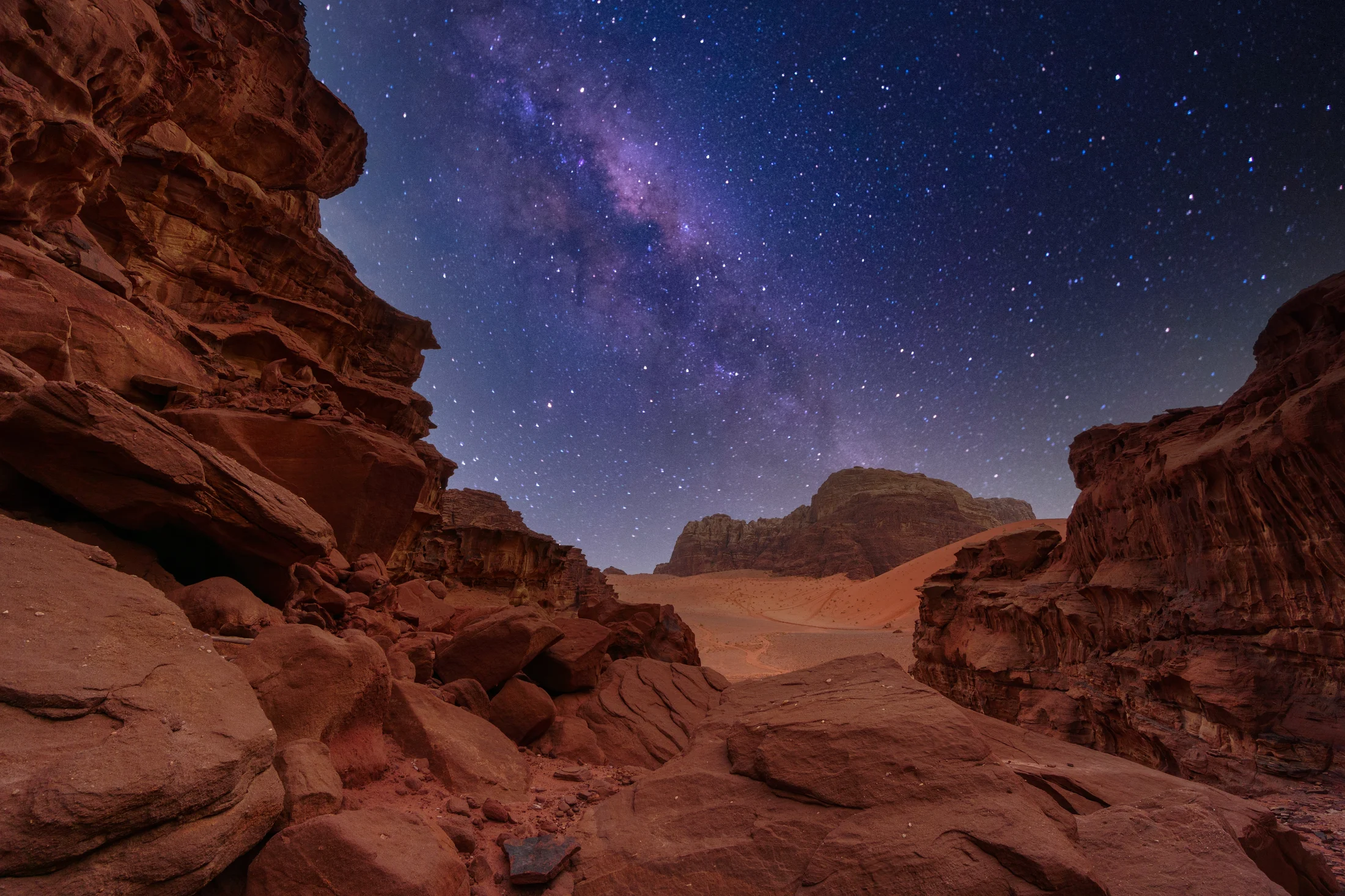 The Milky Way above the sandstone formations and desert floor of Wadi Rum